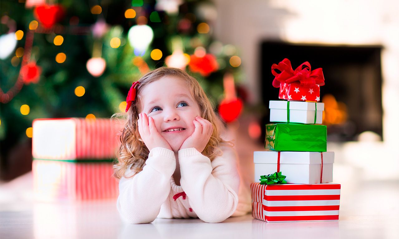 Imagem de uma criança rodeada de presentes de natal.