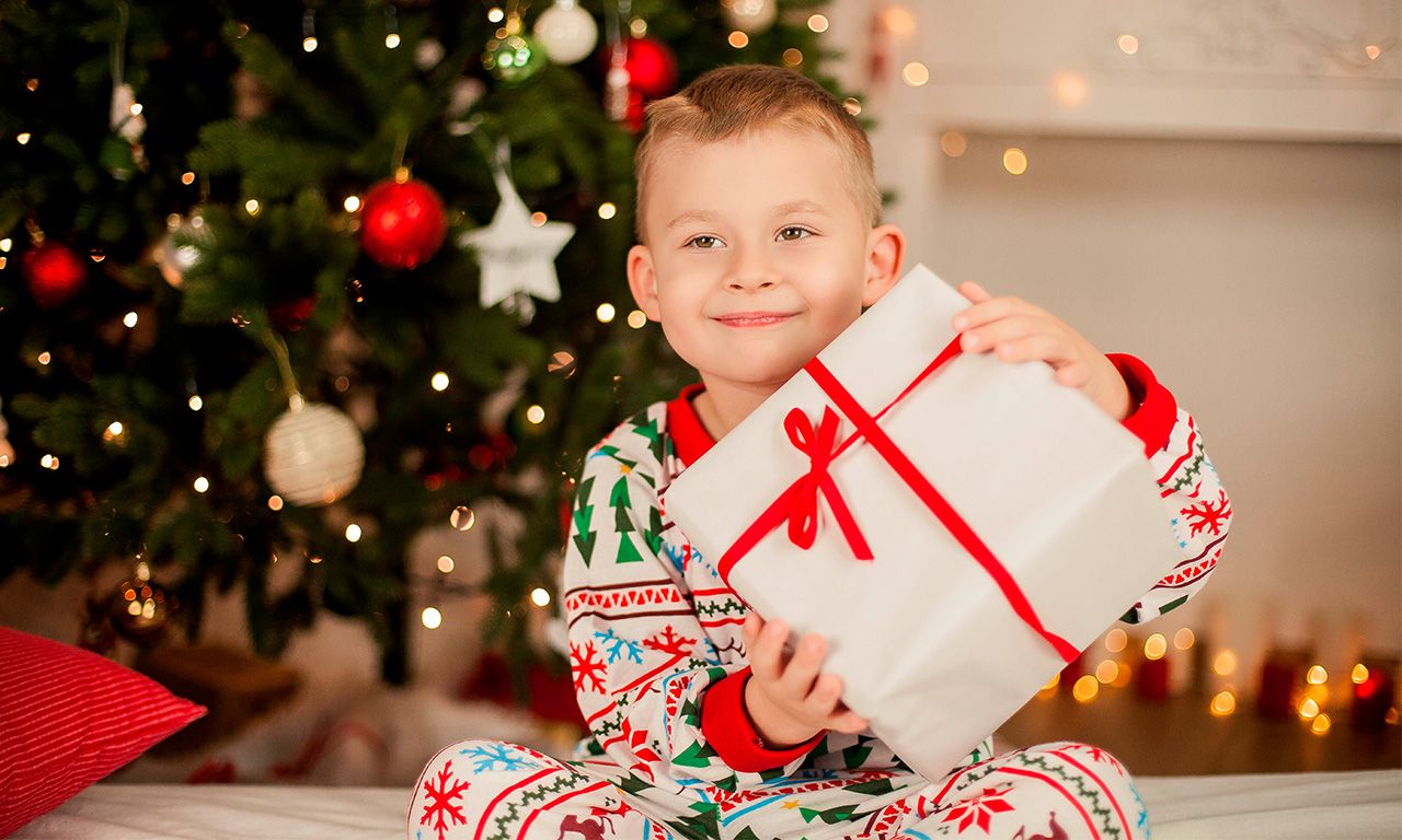 Imagem de um menino segurando um presente de natal.