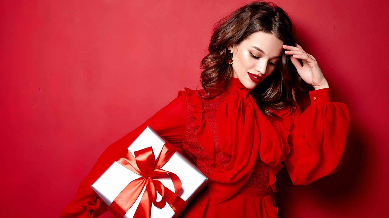Mulher usando vestido vermelho e segurando caixa de presente.