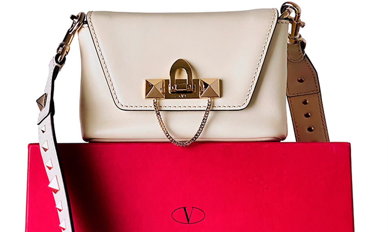 Foto de uma bolsa Valentino na cor off white em cima de uma caixa vermelha da marca.