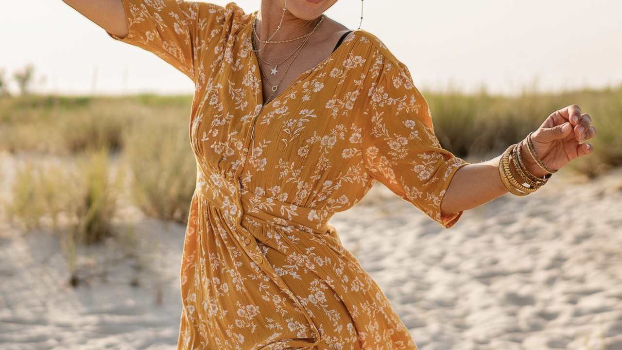 Mulher usando vestido estampado na praia.