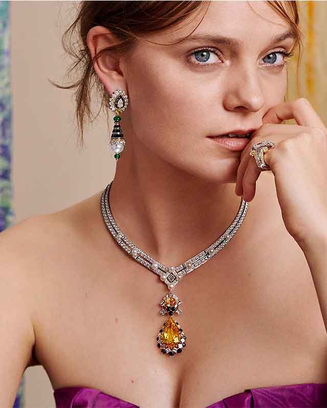 Foto de mulher usando joias Van Cleef and Arpels. Colar, brinco e aneis, uma das top grifes mais caras do mundo.