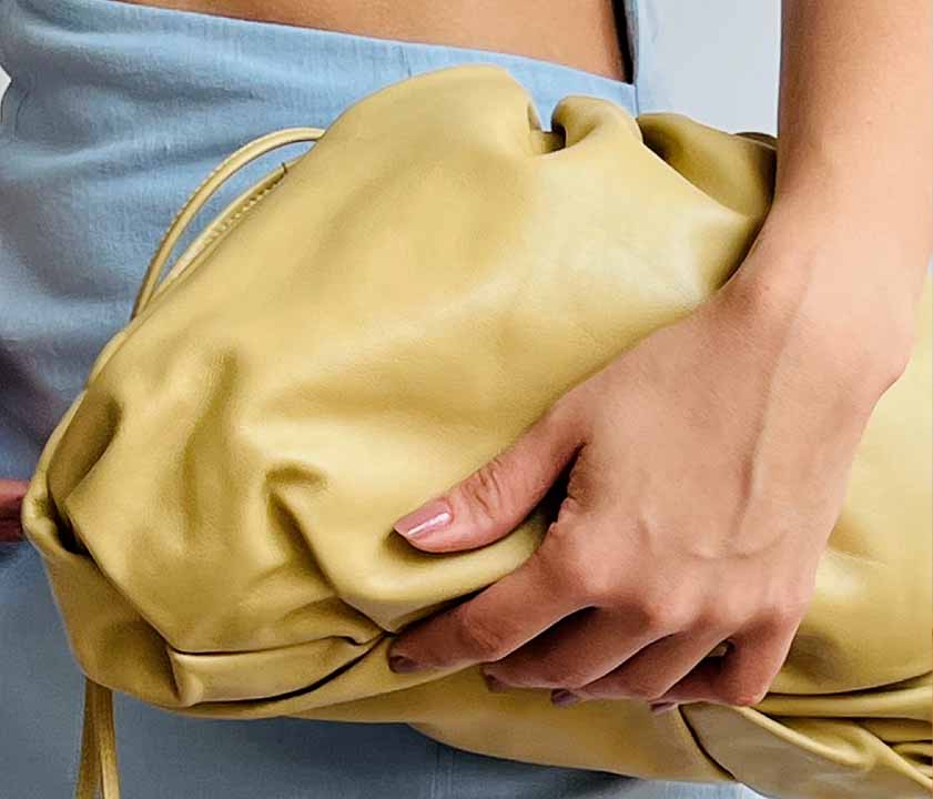 Bolsas Bottega Veneta Pouch sendo segurada na mão de uma mulher.