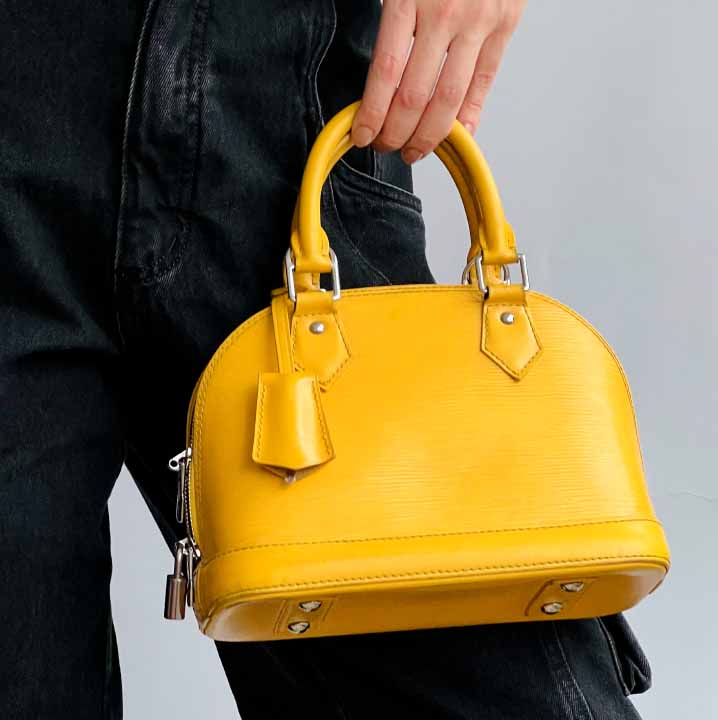 Foto de uma mulher segurando uma das bolsas amarelas da Louis Vuitton pela mão.
