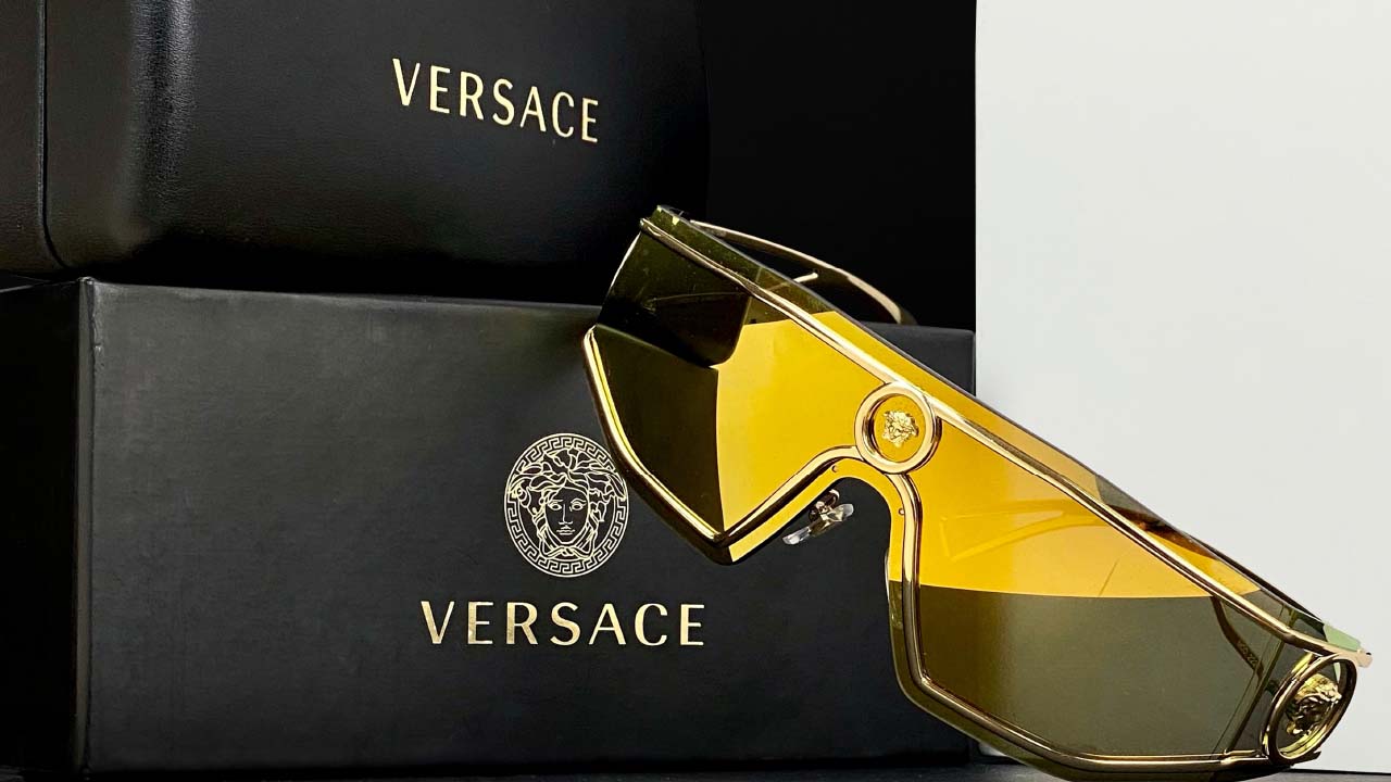 Foto de óculos Versace ao lado de caixas com o símbolo da grife.