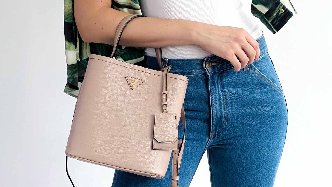 Foto de mulher segurando uma bolsa de uma das melhores marcas italianas, a Prada.