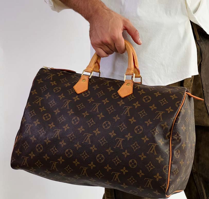 Foto de um homem segurando uma bolsa masculina da Louis Vuitton.