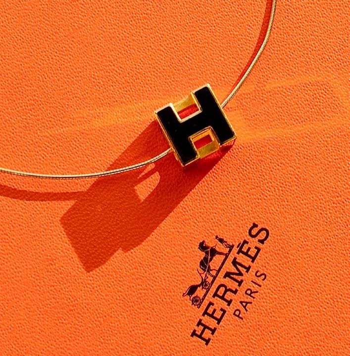 Foto de colar Hermès com a letra H, inicial do nome da marca de luxo francesa.