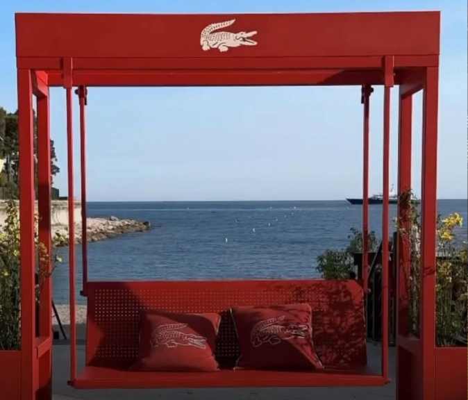 Foto do balanço vermelho com mar ao fundo do Café Lacoste instalado na praia privada Le Méridien Beach Plaza.