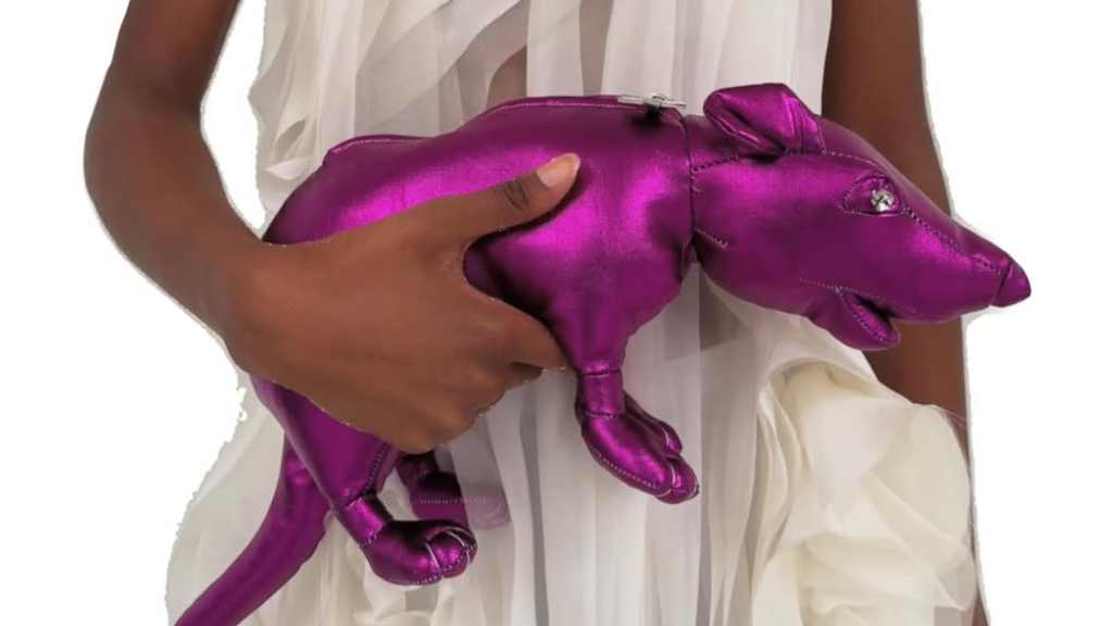 Foto de modelo segurando a Glam Rat Clutch , uma bolsa clutch metalizada em formato de rato desfilada na Copenhagen Fashion Week no desfile de Anne Sofie Madsen em parceria com o artista dinamarquês Esben Weile Kjær.