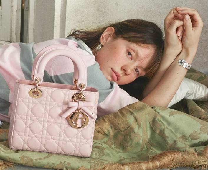 Foto de Mia Goth na Campanha da Dior com uma das Novas Bolsas Lady Dior por Jonathan Anderson que traz um lacinho junto aos pingentes.