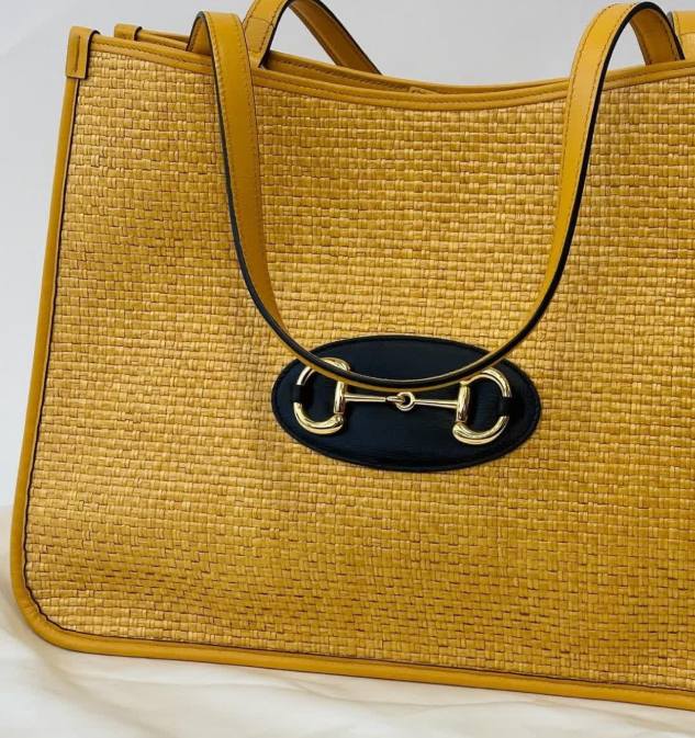Foto de bolsa feita de material natural, ráfia, com couro, da marca de luxo Gucci.