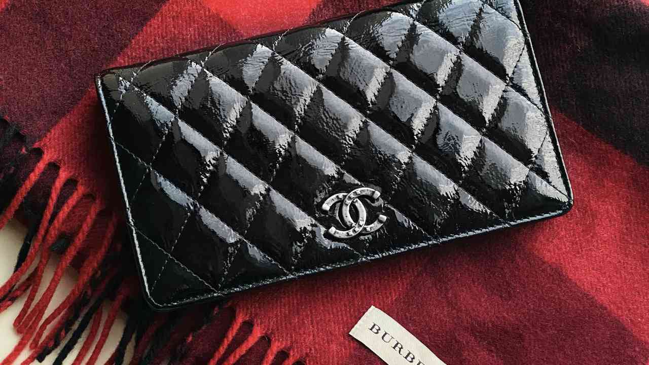 Foto de carteira chanel matelassê vernis em cima de cachecol burberry, acessórios seminovos de luxo favoritos em brechó online.