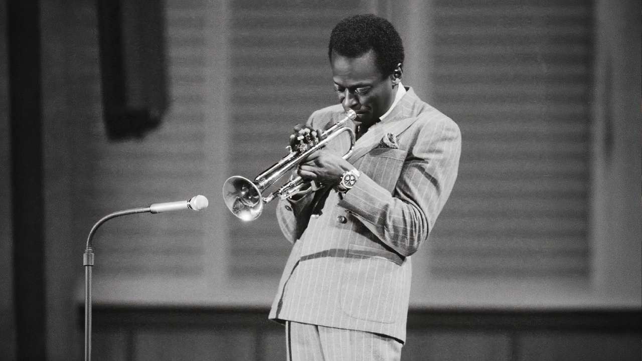 Miles Davis com relógio breitling tocando jazz.